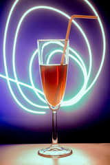 glass of cocktail with background. A glass on the bar in a cafe, restaurant, nightclub or disco. Glass or stemware with alcohol or a cocktail on a colored background.