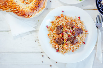 Top view of pilaf or plov with meat on a white plate.