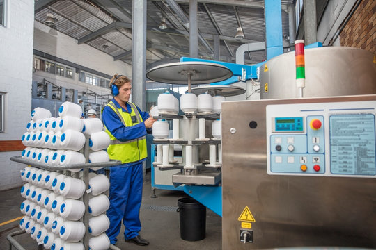 Man wearing ear defenders working with spools in factory