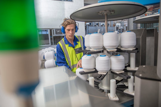 Man wearing ear defenders working with spools in factory