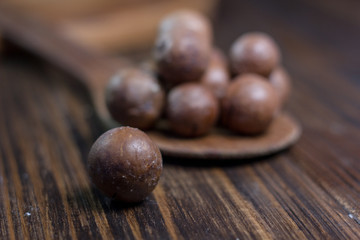 Macadamia nuts on the wooden spoon over the wooden table.