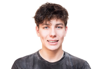 A teenage boy with braces on the lower jaw smiles on a white background
