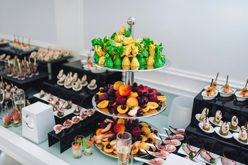 Buffet of different delicious food at a wedding celebration. Goodies for guests. Wedding party. Candy, fruit, meat, drink, champagne, wine, juice.
