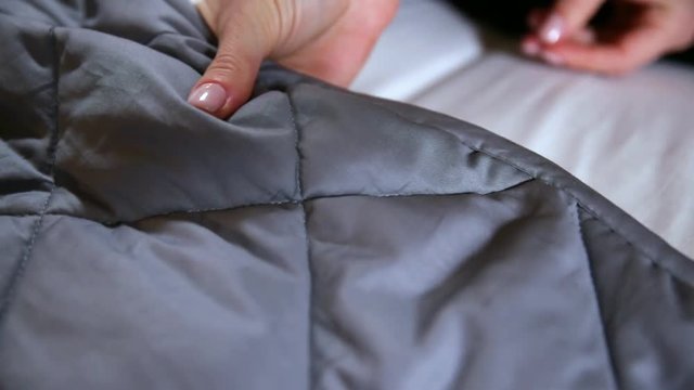Female hand touching soft and clean grey blanket
