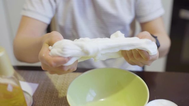 closeup of girl hands squeezing white slime