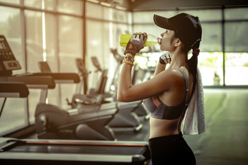 Plakat Sexy Asian woman in sport wear drinking water in gym.