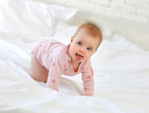 Charming girl 9 months on the bed in pink clothes