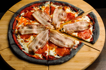 Pepperoni pizza with ham and sausages on black pastry-2.