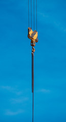 Fototapeta premium Kranhaken mit Kette vor blauem Himmel