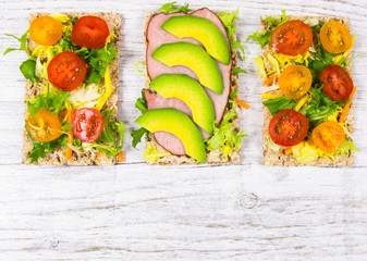 Healthy snack from wholegrain rye crispbread cracker with cherry tomatoes, avocado and salad....