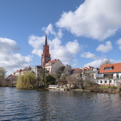 Fototapeta na wymiar Sankt-Marien-Andreas-Kirche im alten Hafen der Stadt Rathenow im Havelland vor blauem Himmel mit Wolken 