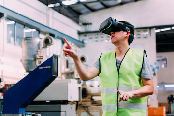 Industrial factory and manfacturing engieering worker wearing VR goggle headset touching in virtual reality simulation alongside heavy duty machines