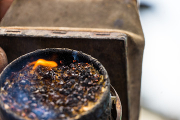 Beekeeper is making a fire in bee smoker. Preparation to Honey Harvest or work with bees. The bee smoker is filled with scobs, sawdust. Fire is visible