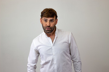 Obraz premium Moda piękny portret przystojny młody człowiek z brązowymi włosami patrząc z ulgą, patrząc w kamerę. Na białym tle