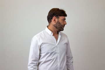Fashion portrait of handsome young man with brown hair looking relieved, facing forwards and...