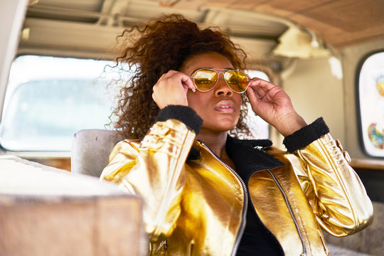 Stylish Edgy African American Woman Wearing Golden Jacket And Sunglasses In Old Van