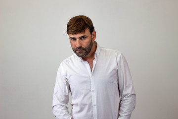 Obraz premium Moda portret przystojny młodzieniec z brązowymi włosami, patrząc zawstydzony, patrząc w kamerę. Na białym tle