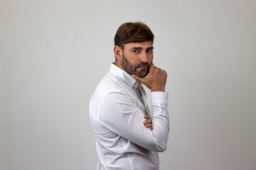 Fashion portrait of handsome young man with brown hair looking concentrated, their back facing the camera and looking at the camera. Isolated on white background.