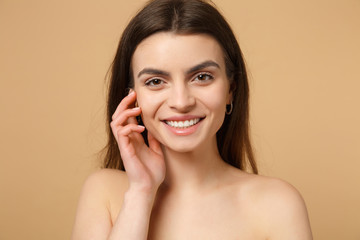 Close up brunette half naked woman 20s with perfect skin, hand on cheek isolated on beige pastel...