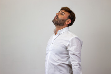 Obraz premium Fashion portrait of handsome young man with brown hair looking overwhelmed, facing forwards and looking at the horizon. Isolated on white background.