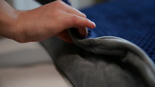 Female hand touching soft and clean grey/blue blanket. Making a bed.
