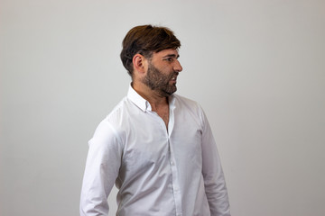 Fashion portrait of handsome young man with brown hair looking disgusted, facing forwards and...