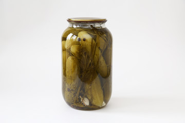glass jar of canned cucumbers with garlic end pepper closed with a metal lid on light background