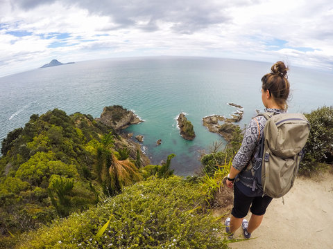 Scenic Landscape View Of Travel Woman Hiking In New Zealand. Young Woman Standing Overlooking Seaside, Turquoise Clergies Sea Water, Whale And White Islands On Background. Whakatane, Bay Of Plenty, NZ