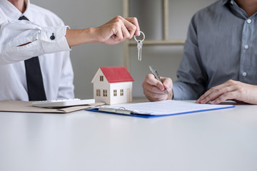 Real estate Sales manager giving keys to customer after signing rental lease contract of sale...