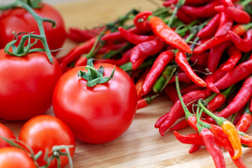 Fresh cherry tomatoes with red peppers on wooden background.