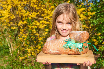 Child girl holding easter lamb cake outside in spring garde