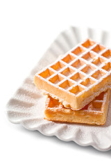 Belgium waffers with sugar powder on ceramic plate isolated on white background.