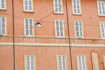 Closed white windows on the red wall of an Italian house. Ravenna, Italy. The background