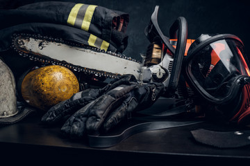 Art composition with safety equipment and respirator, oxygen balon and chainsaw on the table. Dark background. © Fxquadro