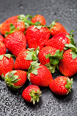 Fresh ripe strawberry with water drops on black.