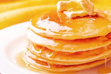 Stack of tasty pancakes with butter on a white plate