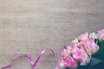 Pink roses and loop isolated on brown cloth Background.