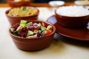 Closeup photo of vegetable salat in bowl with traditional indian dishes at background.