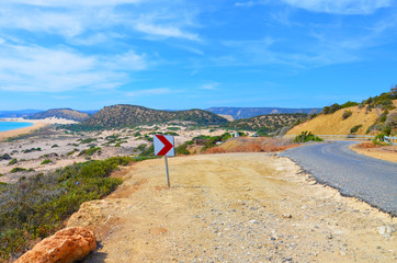 Beautiful view of an amazing bay in Karpas Peninsula, Turkish Northern Cyprus taken on a sunny day from adjacent scenic road. The remote bay is surrounded by small hills with green bushes. 