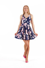 Beautiful young blonde woman in dark blue dress with floral print isolated on white background