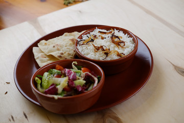 Tradition indian bread with rice and vegetable salat on ceramic plate.