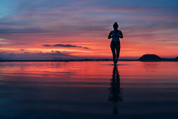 Fototapeta na wymiar Woman meditating in calm yoga pose on sunset sea beach