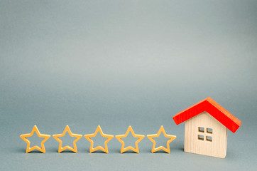 Five stars and a wooden house on a gray background. The concept of the best housing, luxury...