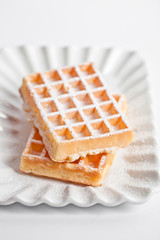 Belgium waffers with sugar powder on ceramic plate isolated on white background.