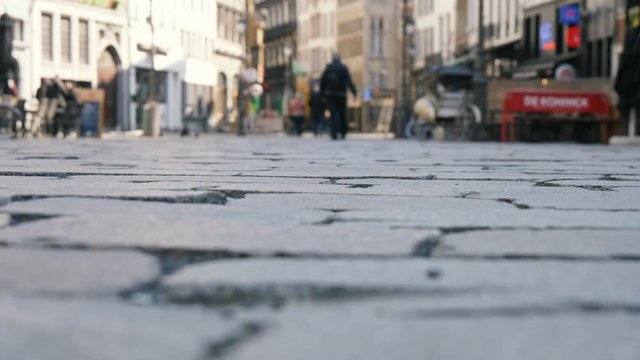 People walking on a cobblestone street with historic buildings in Belgium in slo-mo  