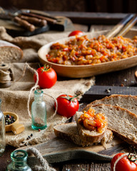 Homemade tasty orange vegetable caviar, ratatouille or ragout on slices of bread and in oval wooden...