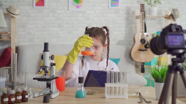 teen blogger in a white coat and goggles in the lab writes the results of the experiment,school project