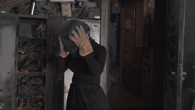 Girl welds steel parts in the workshop
