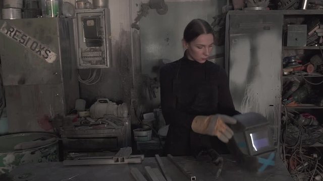 Girl welds steel parts in the workshop