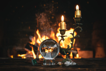 Crystal ball on a magic table on a burning fire flame background.